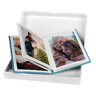 Aufgeklapptes myLeporello Fotobuch mit persönlichen Familienfotos in einer weißen Geschenkbox