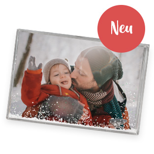 Schüttelrahmen mit Schnee und winterlichem Foto. Es zeigt einen Papa, der seinen kleinen Sohn auf die Wange küsst.